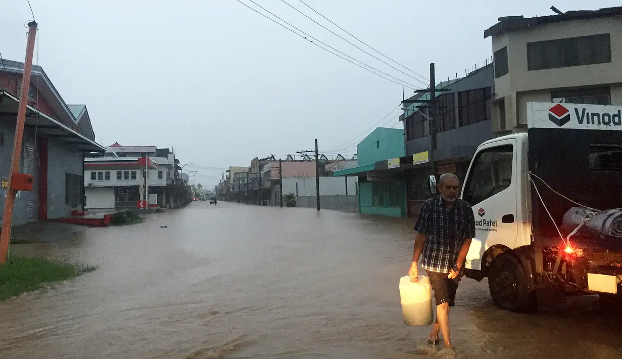 Seorang pria berjalan melewati genangan banjir yang melanda Ba, wilayah barat Fiji, Rabu (6/4). Otoritas Fiji memerintahkan warganya untuk tetap berada di dalam ruangan seiring semakin mendekatnya siklon Tropis Zena. (NAZIAH ALI/MAI LIFE MAGAZINE /AFP)