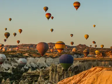 Balon udara membawa wisatawan naik ke langit saat matahari terbit di Kapadokia, Turki, Selasa (7/8). Kapadokia memiliki sejumlah keajaiban alam, khususnya Cerobong Peri (Fairy Chimney). (AP Photo/Emrah Gurel)