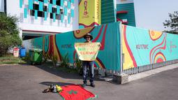 Suporter Maroko, Mohammad Aziz Mrabat menunggu kedatangan bus Timnas Maroko U-17 sambil membentangkan poster bertuliskan "Maroko, menang atau kalah aku tetap mencintaimu" menjelang laga kedua Grup A Piala Dunia U-17 2023 antara Timnas Maroko U-17 melawan Timnas Ekuador U-17 di Stadion Gelora Bung Tomo (GBT), Surabaya, Senin (14/11/2023). (Bola.com/Bagaskara Lazuardi)