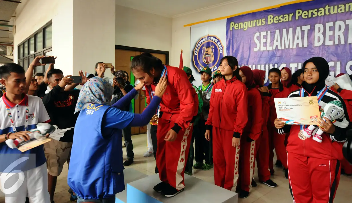 Prosesi pengalungan medali cabang Drum Band Putri nomor LKKB 2000 meter PON XIX Jabar di Stadion Pakansari, Bogor, Rabu (14/9). Tim Provinsi Banten meraih emas di nomor LKKB 2000 meter putri dan LKKB 4000 putra. (Liputan6.com/Helmi Fithriansyah)