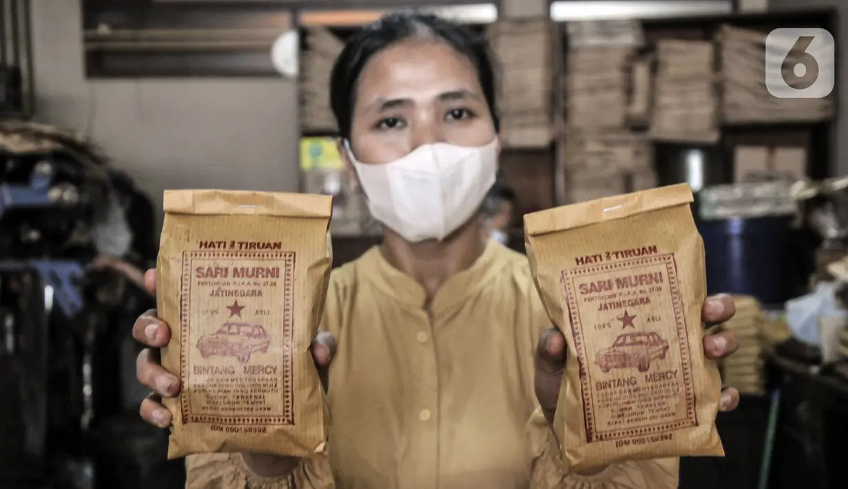 Pekerja menunjukkan kopi yang siap dipasarkan di toko kopi Sari Murni, Jatinegara, Jakarta Timur, Selasa (4/1/2021). Toko kopi yang berdiri sejak tahun 1952 ini juga dikenal dengan Kopi Cap Sedan. (merdeka.com/Iqbal S. Nugroho)