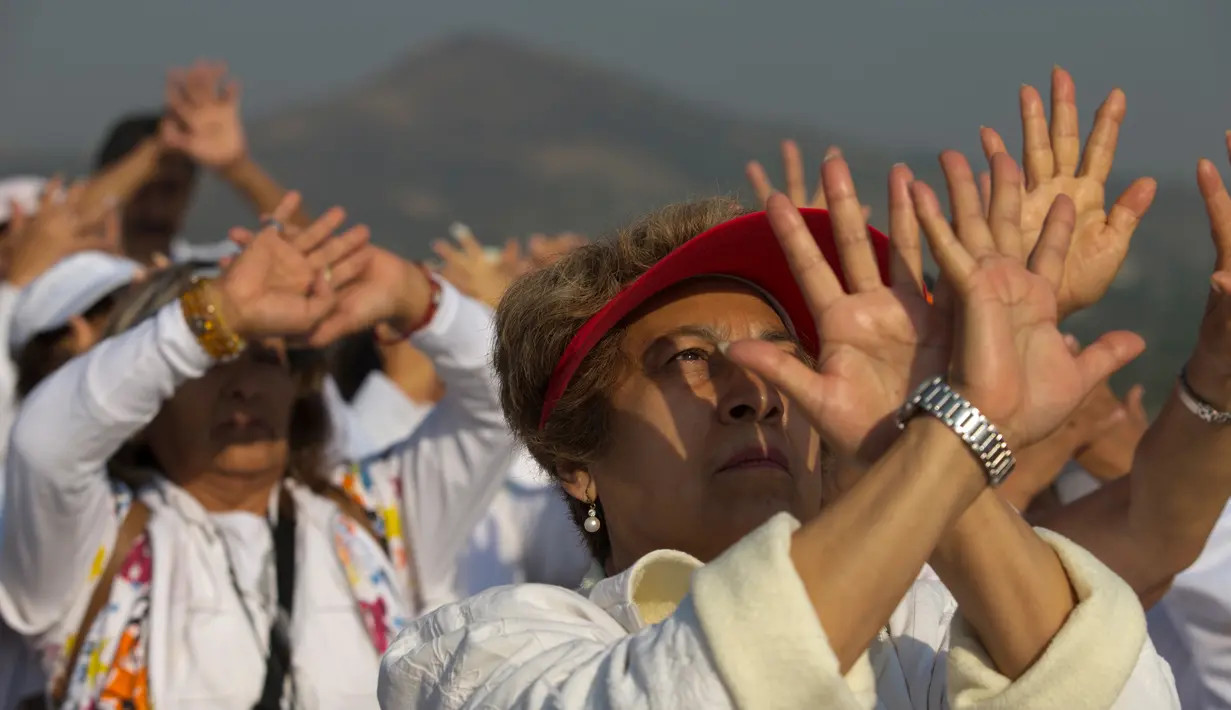 Wisatawan mengangkat tangan merasakan hangatnya sinar mentari pada upacara menyambut fenomena equinox di depan Piramida Matahari, Teotihuacan, Meksiko, Senin (20/3). Equinox terjadi dua kali dalam setahun, yakni Maret dan September. (AP/Rebecca Blackwell)