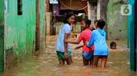 Anak-anak bermain banjir yang melanda kawasan Bidara Cina, Kecamatan Jatinegara, Jakarta Timur, Selasa (25/2/2020). Baru satu hari air surut, kawasan Bidara Cina yang bersebelahan dengan Kali Ciliwung kembali mengalami banjir. (merdeka.com/magang/ Muhammad Fayyadh)