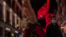 Orang-orang yang memakai masker berjalan di pusat kota Madrid, Rabu (22/12/2021). Perdana Menteri Spanyol Pedro Sanchez mengadakan rapat Kabinet khusus untuk mengesahkan undang-undang yang mewajibkan penggunaan masker di luar ruangan di tengah lonjakan rekor kasus COVID-19. (AP Photo/Manu Fernandez)