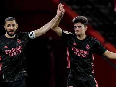 Striker Real Madrid, Karim Benzema (kiri) melakukan selebrasi usai mencetak gol keempat timnya ke gawang Granada dalam laga lanjutan Liga Spanyol 2020/2021 pekan ke-36 di Los Carmenes Stadium, Granada, Kamis (13/5/2021). Real Madrid menang 4-1 atas Granada. (AP/Fermin Rodriguez)