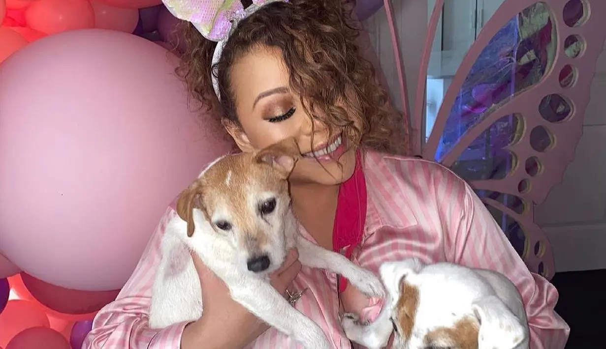 Mariah Carey tak ketinggalan mengunggah foto dirinya merayakan Paskah. Agak berbeda, Mariah Carey menunjukkan potret dirinya bersama dua anjing peliharaannya. Mariah Carey dibalut piyama bergaris merah muda, lengkap dengan bando telinga kelinci, dan riasan wajah bold. Ruangan tempatnya berfoto juga tampak telah didekorasi dengan balon beragam ukuran bernuansa merah muda yang gemas. Foto: Instagram.