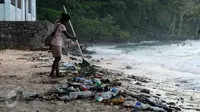 Warga berusaha membersihkan sampah di pantai Pasir Putih, Manokwari, Papua Barat, Senin (15/8/2016). Tampak, sisa botol berserakan, kondisi ini bisa mengurangi daya tarik wisatawan menikmati keindahan alam Papua Barat. (Liputan6.com/Helmi Fithriansyah)