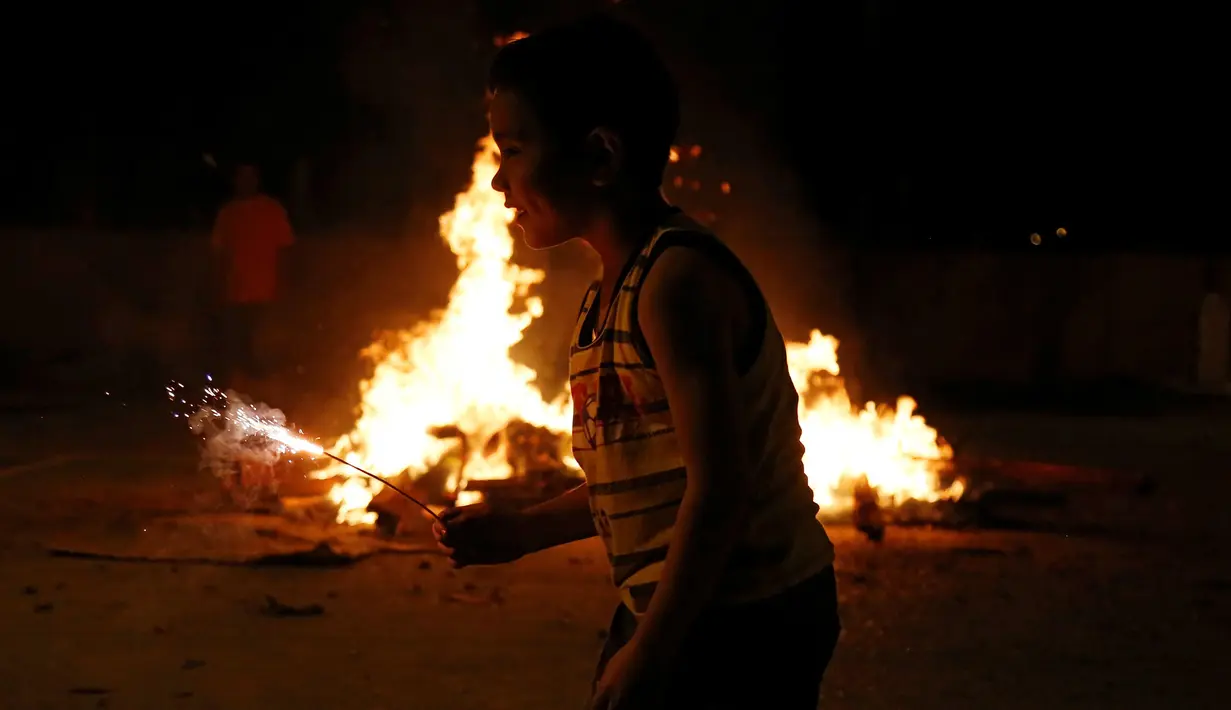 Seorang anak bermain didepan pinata Donald Trump yang telah dibakar saat perayaan tradisional, Pembakaran Iblis, Guatemala (7/12). Di tempat tersebut roh jahat itu direpresentasikan dalam bentuk tokoh politik kontemporer. (Reuters/Luis Echeverria)