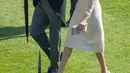 Duke dan Duchess of Sussex, Pangeran Harry dan Meghan Markle menghadiri pesta kebun Istana Buckingham di London, Selasa (22/5). Midi dress dari Goat dengan aksen lengan sheer itu tampak manis membalut tubuh Meghan Markle. (Ian Vogler/Pool Photo via AP)