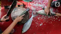 Pedagang memotong dan membersihkan sisik ikan bandeng dari air tambak di kawasan Rawa Belong, Jakarta, Rabu (10/2/2021). Menjelang perayaan Imlek atau Tahun Baru China, penjualan ikan bandeng tambak sepi pembeli akibat pandemi Covid-19 dibanding tahun sebelumnya. (Liputan6.com/Fery Pradolo)