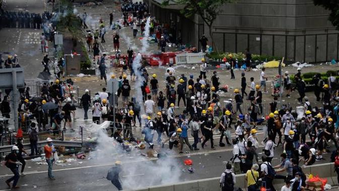 Pengunjuk rasa menghindari gas air mata yang ditembakan oleh polisi anti huru hara di luar gedung Dewan Legislatif, Hong Kong, Rabu (12/6/2019). Polisi Hong Kong telah menggunakan gas air mata ke arah ribuan demonstran yang menentang RUU ekstradisi yang sangat kontroversial. (AP Photo/Vincent Yu)