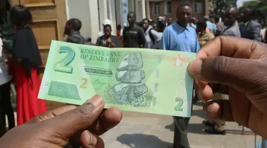Seorang pria memegang salah satu uang kertas baru yang dikeluarkan Reserve Bank of Zimbabwe di Harare, 12 November 2019. Pemerintah Zimbabwe memperkenalkan kembali mata uang negaranya setelah hampir satu dekade terakhir menggunakan mata uang negara lain untuk bertransaksi. (AP/Tsvangirayi Mukwazhi)