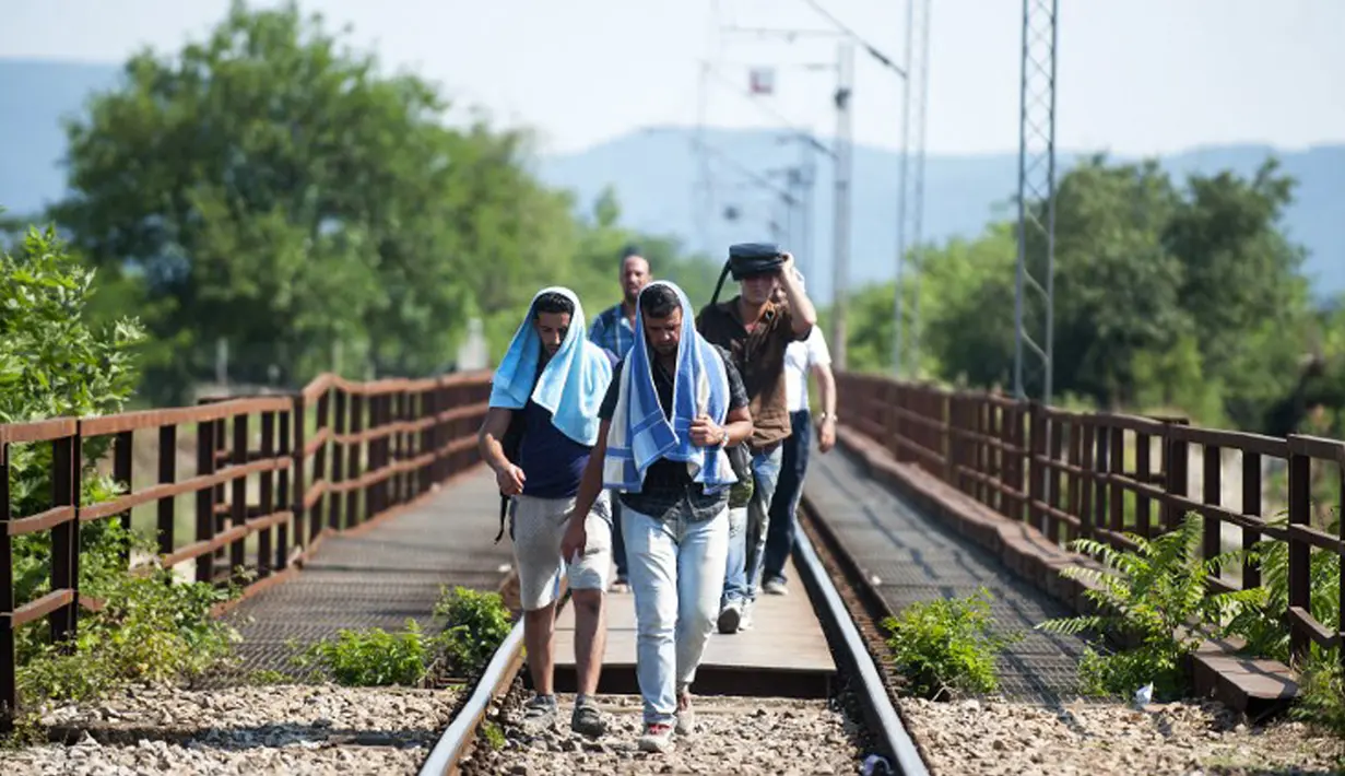 Sejumlah pria berjalan menyusuri rel kereta api saat perjalanan menuju Gevgelija, wilayah perbatasan Macedonia-Yunani, Kamis (9/7/2015). Mereka menempuh ribuan kilometer agar dapat mengejar kereta api tujuan Serbia. (AFP PHOTO/Robert ATANASOVSKI)