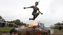 Seorang wanita melompat di atas api saat mengikuti kompetisi lari ekstrim di Zhodino, Minsk timur, Belarus, 26 September 2015. (REUTERS/Vasily Fedosenko)