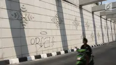 Pengendara motor melintasi coretan di dinding underpass atau lintas bawah Matraman, Jakarta Selatan, Rabu (2/5). Underpass yang belum genap sebulan diresmikan untuk diuji coba tersebut dihiasi coretan tangan jahil. (Liputan6.com/Arya Manggala)