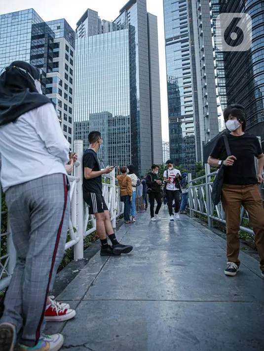 Warga berkumpul diatas JPO tanpa atap di Jakarta, Minggu (12/9/2021). Kasus baru positif Covid-19 di Indonesia per Minggu (12/9) bertambah sebanyak 3.779 kasus Jumlah tersebut membuat total kasus virus corona sejak awal pandemi mencapai 4.167.511 kasus. (Liputan6.com/Faizal Fanani)