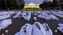 Spanduk besar bertuliskan "Biden: Gencatan Senjata Sekarang" bersama dengan kantong mayat palsu berwarna putih, dipajang di depan Gedung Putih pada senja, di Washington, Rabu (15/11/2023). (AP Photo/Andrew Harnik)