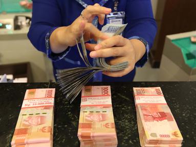 Petugas tengah menghitung uang rupiah di Bank BUMN, Jakarta, Selasa (17/4). Mengacu data Bloomberg, rupiah siang ini pukul 12.00 WIB di pasar spot exchange sebesar Rp 13.775 per dolar AS atau menguat 4,7 poin. (Liputan6.com/Angga Yuniar)
