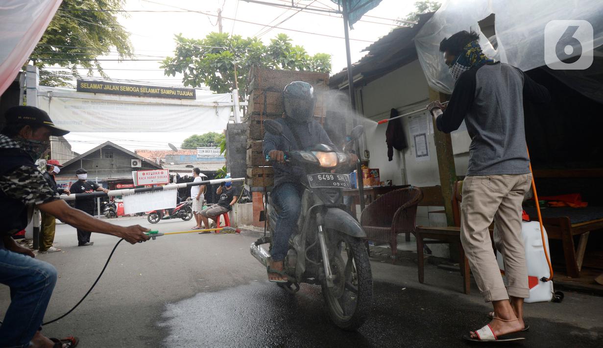 Sejumlah pemuda menyemprotkan cairan disinfektan kepada orang yang akan memasuki RW 10 di kawasan Tanah Kusir, Kelurahan Kebayoran Lama Selatan, Jakarta, Rabu (8/4/2020). Warga menerapkan akses satu pintu masuk pemukiman tersebut untuk mencegah penyebaran corona COVID-19. (merdeka.com/Dwi Narwoko)