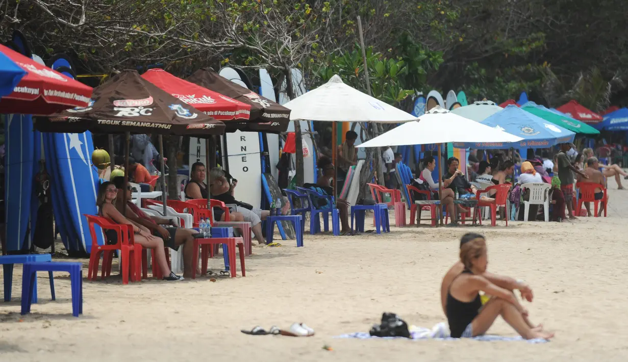 Sejumlah turis menikmati pantai Kuta di pulau pariwisata Indonesia di Bali (4/1). Pantai Kuta terkenal memiliki ombak yang bagus untuk olahraga selancar, terutama bagi peselancar pemula. (AFP Photo/Sony Tunbelaka)