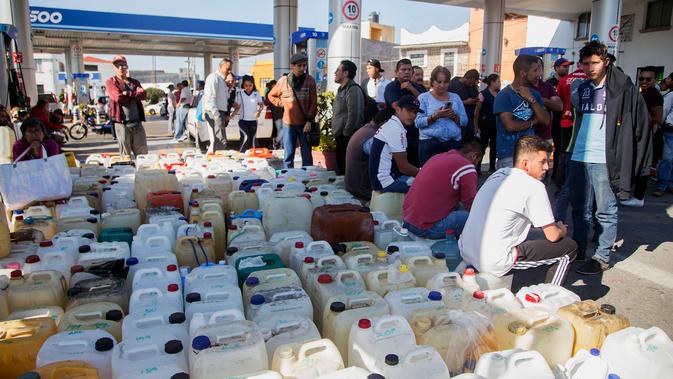 Warga antre menggunakan jerigen di tengah kelangkaan BBM di sebuah SPBU di Morelia, Meksiko, Selasa (8/1). Antrean disebabkan pasokan BBM ke beberapa negara bagian di Meksiko mengalami kekurangan akibat kasus pencurian bahan bakar. (ENRIQUE CASTRO/AFP)