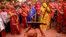 Perempuan India dari desa Barsana memukuli seorang warrga dari Nandgoan dengan tongkat kayu selama perayaan festival Lathmar holi di Barsana, India, Selasa (23/3/2021). Para pria biasanya membawa perisai untuk melindungi diri mereka sendiri sementara wanita memukuli mereka dengan tongkat. (AP Photo)