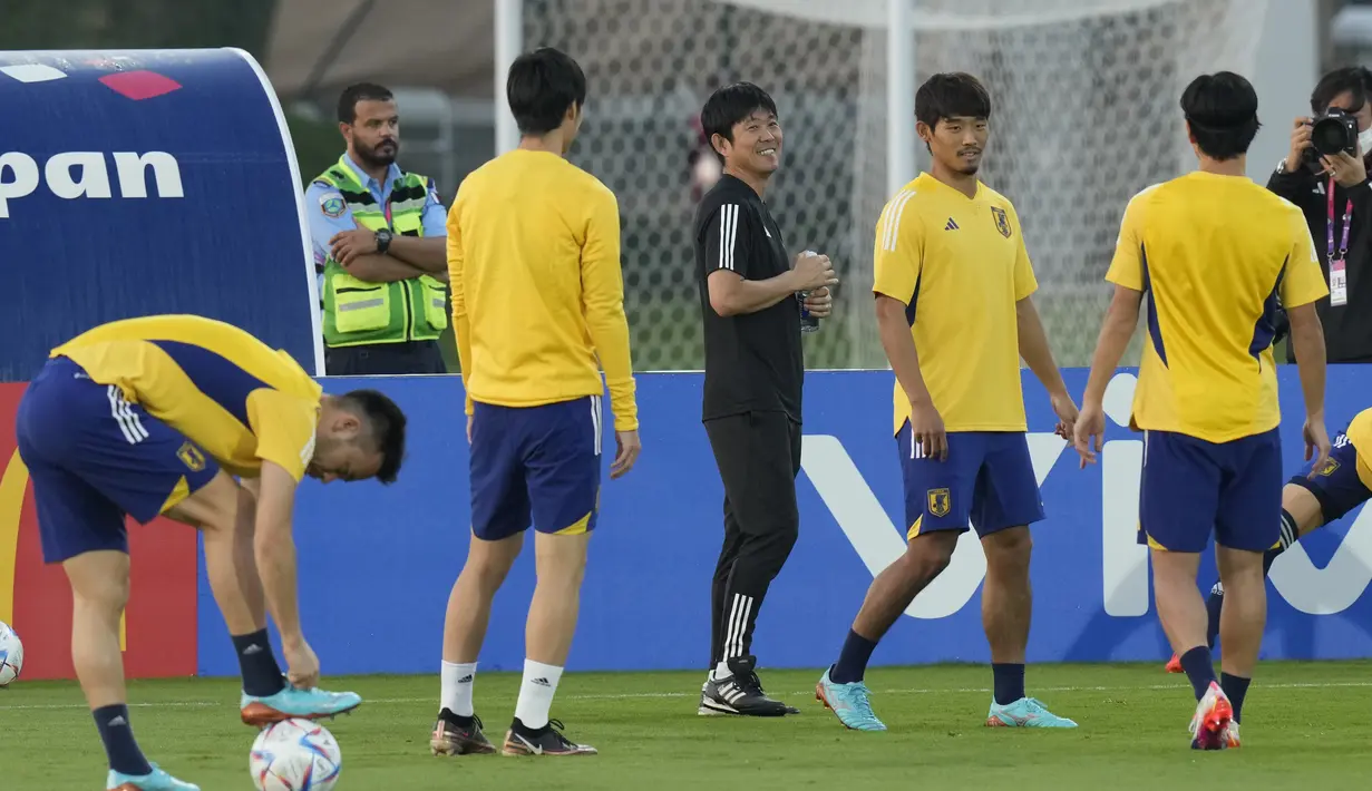 Pelatih Jepang, Hajime Moriyasu (tengah) tersenyum saat para pemain melakukan pemanasan selama latihan di Doha, Qatar, Minggu, 4 Desember 2022. Jepang akan bertanding melawan Kroasia pada babak 16 besar Piala Dunia 2022 Qatar yang akan digelar di Stadion Al Janoub, Al Wakrah, pada Senin (5/12) malam. (AP Photo/Eugene Hoshiko)