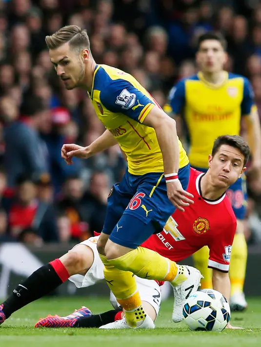 Gelandang Arsenal, Aroon Ramsey (kiri) berusaha melewati gelandang Ander Herrera saat Laga Liga Premier Inggris di Stadion Old Trafford, Minggu (17/5/2015). Manchester United bermain imbang 1-1 atas Arsenal. (Reuters/ Phil Noble)