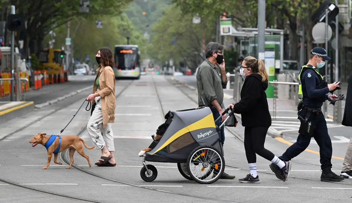 Orang-orang berjalan-jalan dengan anjing mereka di Melbourne, Australia, Kamis (30/9/2021). Melbourne bergulat dengan lonjakan infeksi Covid-19 di mana sebanyak 1.438 kasus dilaporkan, jumlah harian terbesar sejak awal pandemi. (William WEST / AFP)