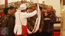 Salah satu anggota Aliansi Masyarakat Adat Nusatara memberikan kain kepada Presiden Joko Widodo di Istana Negara, Jakarta, Rabu (22/3). Dalam pertemuan tersebut dibahas persoalan tanah adat. (Liputan6.com/Angga Yuniar)