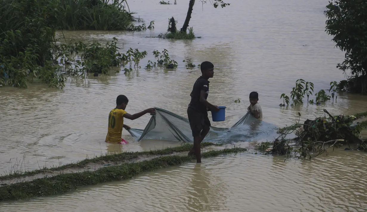 Pengungsi memancing di air banjir menyusul hujan deras di kamp pengungsi Rohingya di Kutupalong, Bangladesh Bangladesh (28/7/2021). Hujan deras berhari-hari telah membuat ribuan tempat penampungan di berbagai kamp pengungsi Rohingya di Bangladesh Selatan terendam air. (AP Photo/Syafiqur Rahman)