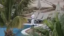 Seorang staf membersihkan kolam renang hotel H10 Costa Adeje Palace di La Caleta, di Pulau Canary Tenerife, Spanyol, Kamis  (27/2/2020). Pemerintah Spanyol mengatakan sekitar 1.000 orang di Hotel H10 tersebut diisolasi usai adanya temuan positif virus corona COVID-19. (AP Photo/Joan Mateu)