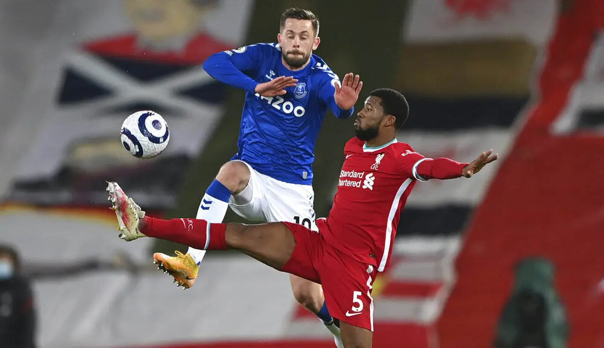 Gelandang Liverpool, Georginio Wijnaldum, berebut bola dengan pemain Everton, Gylfi Sigurdsson, pada laga Liga Inggris di Stadion Anfield, Minggu (21/2/2021). Everton menang 2-0 atas Liverpool. (Lawrence Griffiths/ Pool via AP)