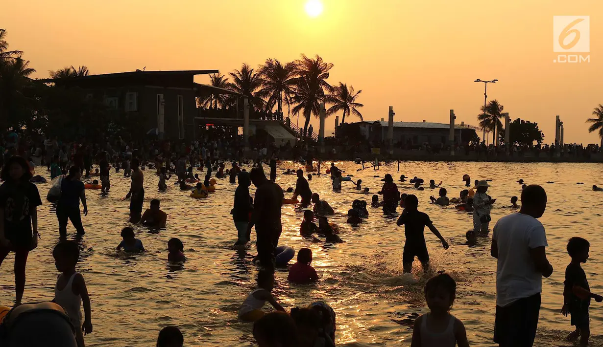 Pengunjung berenang jelang matahari tenggelam di kawasan wisata Pantai Karnaval Ancol, Jakarta, Sabtu (16/6). H+1 libur Lebaran, jumlah pengunjung di Ancol mencapai 88.143 orang. (Liputan6.com/Immanuel Antonius)
