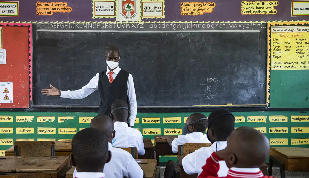 Seorang guru menyambut kembali siswa selama pelajaran di kelas pada hari pertama pembukaan kembali sekolah di Kampala pada 10 Januari 2022. Sekolah-sekolah di Uganda dibuka kembali untuk siswa pada Senin, mengakhiri penutupan sekolah terlama di dunia akibat pandemi COVID-19. (Badru KATUMBA/AFP)