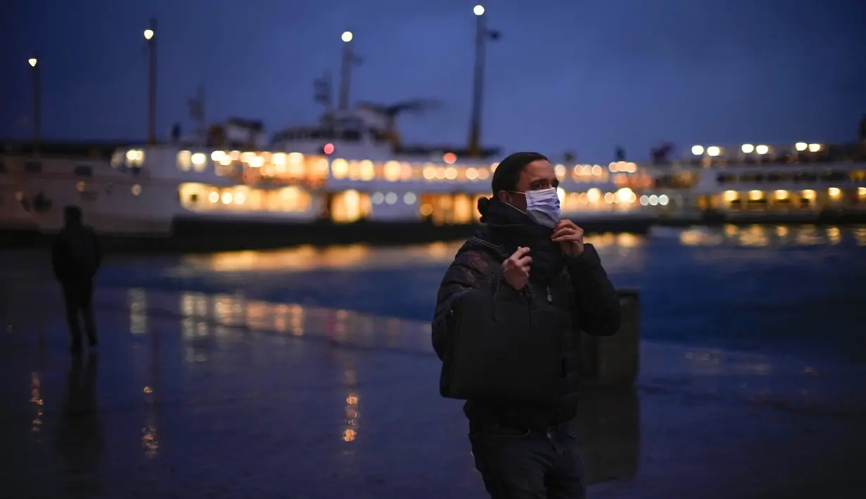 Seorang pria menyesuaikan masker pelindungnya untuk mencegah penyebaran COVID-19 saat dia berjalan di terminal feri Karakoy di Istanbul, Turki  (11/1/2022). Meskipun ada lonjakan, negara tersebut belum mempertimbangkan untuk memberlakukan pembatasan baru. (AP Photo/Francisco Seco)