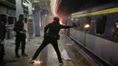 Seorang pelajar melempar bom molotov ke dalam kereta yang terparkir di Stasiun MTR Chinese University, Hong Kong, Rabu (13/11/2019). Gerakan antipemerintah Hong Kong yang telah berlangsung selama lima bulan bertindak semakin keras. (AP Photo/Kin Cheung)