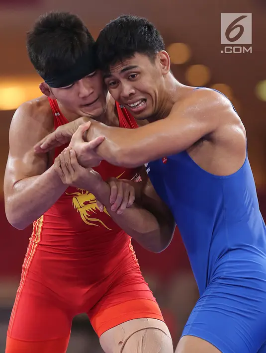 Pegulat putra Indonesia, Muhammad Aliansyah dan Zhang Gaoquan dari China saling mengunci saat bertarung pada kelas putra 67 Kg Asian Games 2018 di arena gulat JCC Senayan, Selasa (21/8). (Liputan6.com/Fery Pradolo)