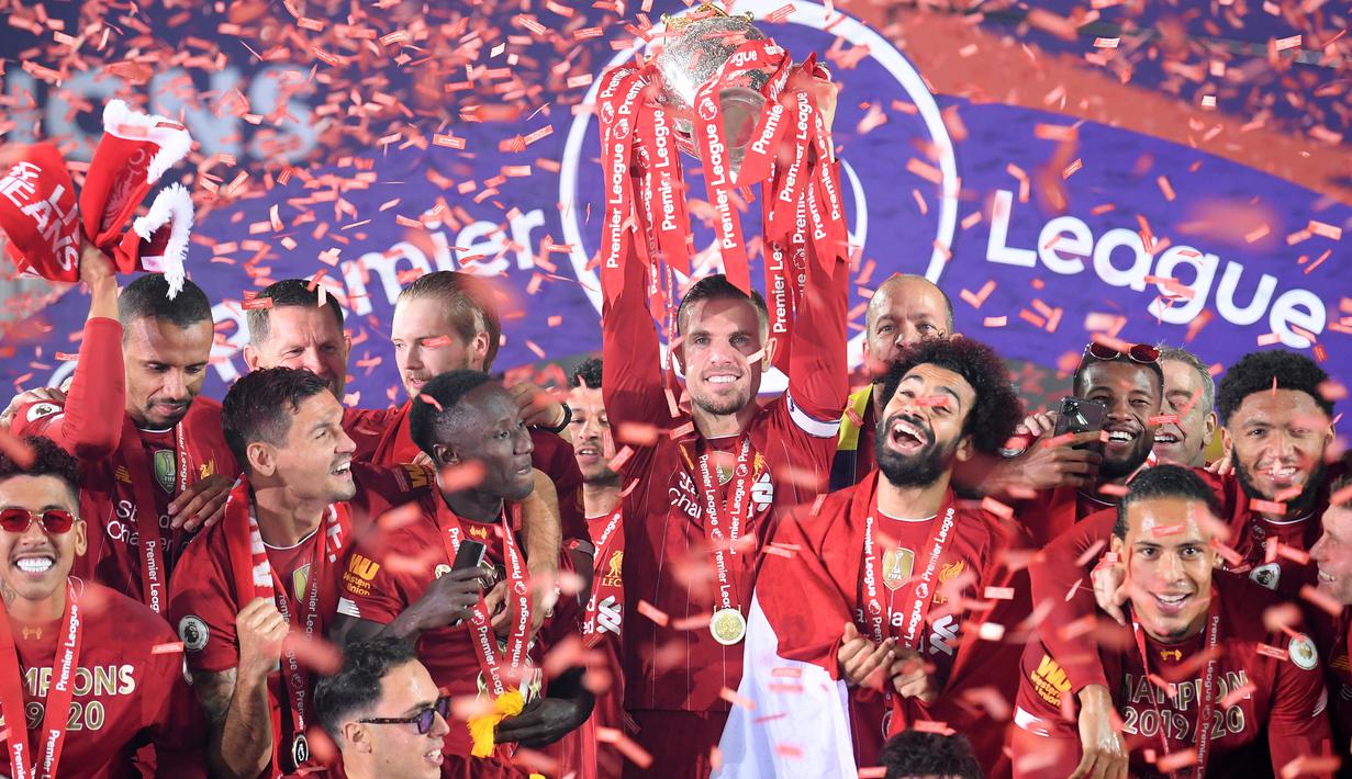 Gelandang Liverpool, Jordan Henderson, mengangkat trofi juara Premier league 2019-2020 di Stadion Anfield, Kamis (23/7/2020) dini hari WIB. Prosesi angkat trofi juara ini dilakukan usai pertandingan Liverpool melawan Chelsea. (AFP/Laurence Griffiths/pool)
