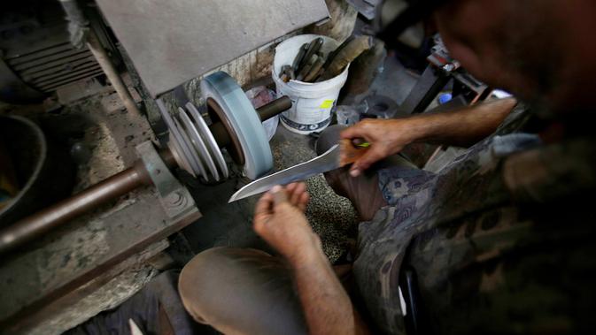 Seorang pria Palestina menajamkan pisau yang akan digunakan untuk menyembelih hewan kurban dalam perayaan Idul Adha di sebuah lokakarya di Kota Gaza, 28 Juli 2020. Idul Adha merupakan salah satu tanggal penting dalam kalender Islam. (AP Photo/Hatem Moussa)