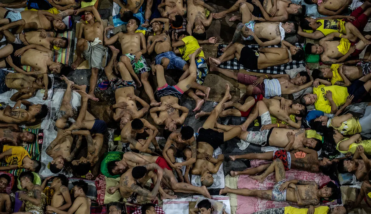 Narapidana tidur di lapangan basket terbuka di penjara Quezon City di Manila, Filipina, 19 Juli 2016. Sejak dibangun enam dekade lalu sudah terdapat 3.800 narapidana yang mendekam dibalik jeruji rutan yang diperuntukan bagi 800 orang itu. (Noel Celis/AFP)