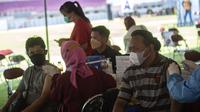 Warga menerima vaksin virus corona COVID-19 Sinovac di pusat vaksinasi massal darurat di lapangan sepak bola di Surabaya, Jawa Timur, Kamis (30/9/2021). Vaksinasi ini dalam rangka percepatan penanganan COVID-19 dan pemulihan ekonomi nasional. (Juni Kriswanto/AFP)