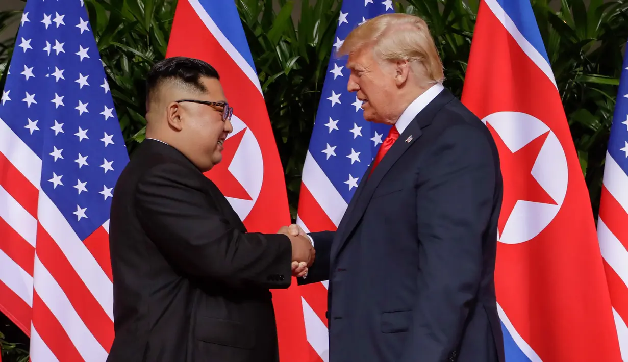 Presiden Amerika Serikat (AS) Donald Trump  berjabat tangan dengan Pemimpin Korea Utara, Kim Jong-un dalam pertemuan bersejarah di resor Capella, Pulau Sentosa, Singapura, Selasa (12/6). Trump dan Kim berjabat tangan untuk pertama kalinya. (AP/Evan Vucci)