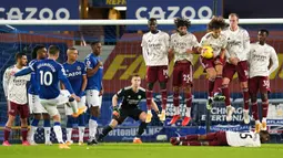 Gelandang Arsenal, Ainsley Maitland-Niles berbaring di belakang rekan-rekannya yang membuat pagar hidup untuk menjaga tendangan bebas yang dilakukan gelandang Everton, Gylfi Sigurdsson dalam laga lanjutan Liga Inggris 2020/21 di Goodison Park, Sabtu (19/12/2020). (AFP/Jon Super/Pool)