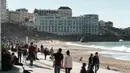 Warga dan turis menikmati cuaca musim dingin yang hangat saat berjalan di sepanjang garis pantai di Biarritz, Perancis (17/2). Pantai Biarritz yang berbatasan dengan Spanyol ini termasuk salah satu wilayah termahal di Prancis. (AFP Photo/Iroz Gaizka)