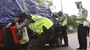 Petugas kepolisian melakukan pengecekan terhadap kendaraan yang keluar Tol Merak, Banten, Senin (18/5/2020). Pemeriksaan (check point) tersebut terkait larangan mudik guna penyekatan atau memeriksa kemungkinan pemudik yang akan keluar dari wilayah Jabodetabek. (Liputan6.com/Angga Yuniar)