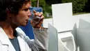 Ilmuwan Belgia, Sebastiaan Derese meminum air dari mesin buatannya yang bisa mengubah air seni menjadi air yang layak diminum dan menjadi pupuk dengan bantuan energi matahari, di University of Ghent, Belgia, Selasa (26/7). (REUTERS/Francois Lenoir)