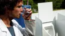Ilmuwan Belgia, Sebastiaan Derese meminum air dari mesin buatannya yang bisa mengubah air seni menjadi air yang layak diminum dan menjadi pupuk dengan bantuan energi matahari, di University of Ghent, Belgia, Selasa (26/7). (REUTERS/Francois Lenoir)