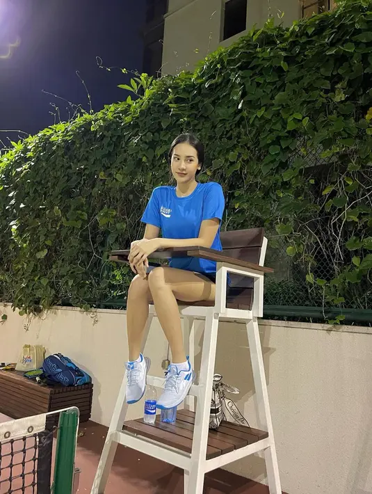 Anya Geraldine duduk dikursi wasit saat berada di lapangan tenis. Ia tampil sporty dengan celana hitam pendek dan atasan berwarna putih. Anya juga mengikat rambut panjangnya. (Instagram/anyageraldine)