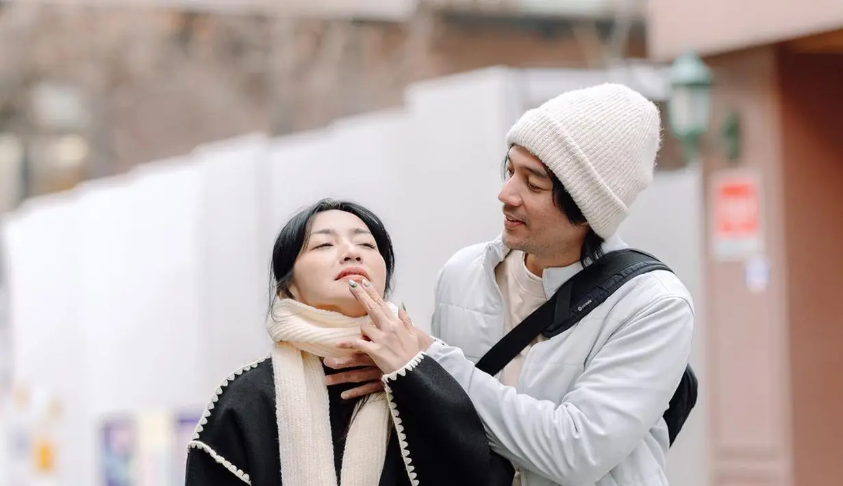 Hesti kenakan outer hitam dengan list putih dan rok kulit panjang. Ditutup dengan puffy shoes dan syal rajut ivory. [@hestipurwadinata]